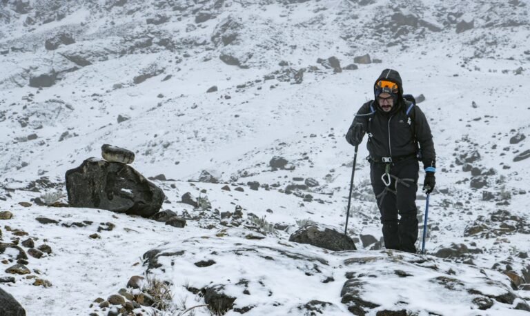 Man hiking through snowy mountain terrain, showcasing winter expedition wear and determination – Dog Gear