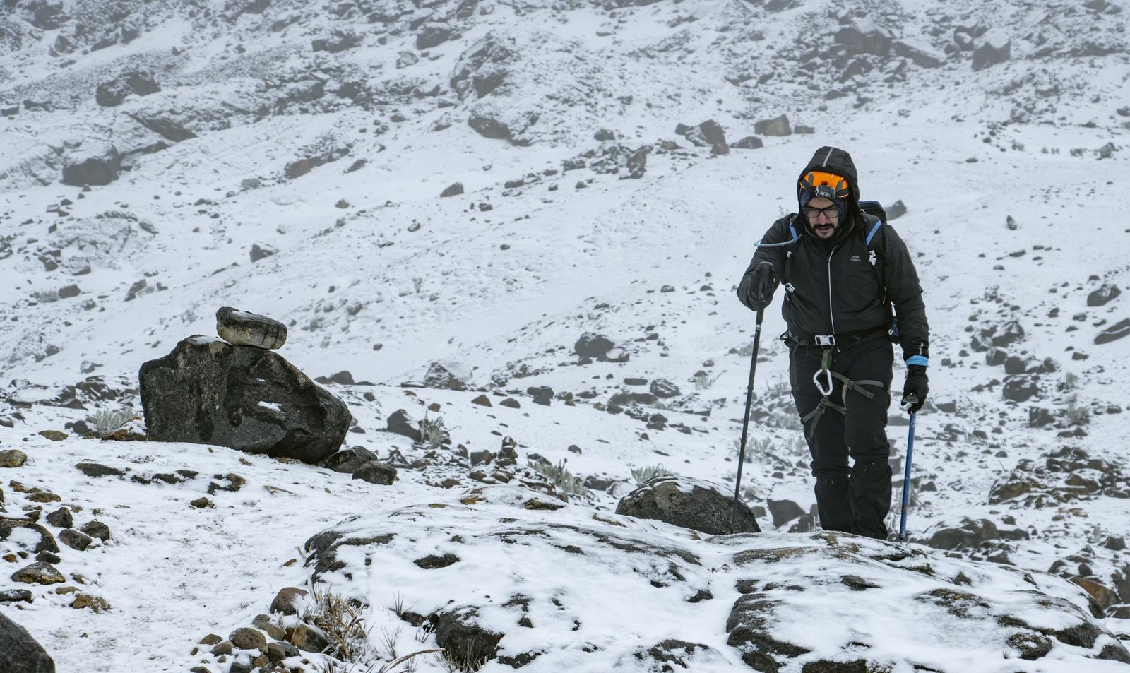 Man hiking through snowy mountain terrain, showcasing winter expedition wear and determination – Dog Gear