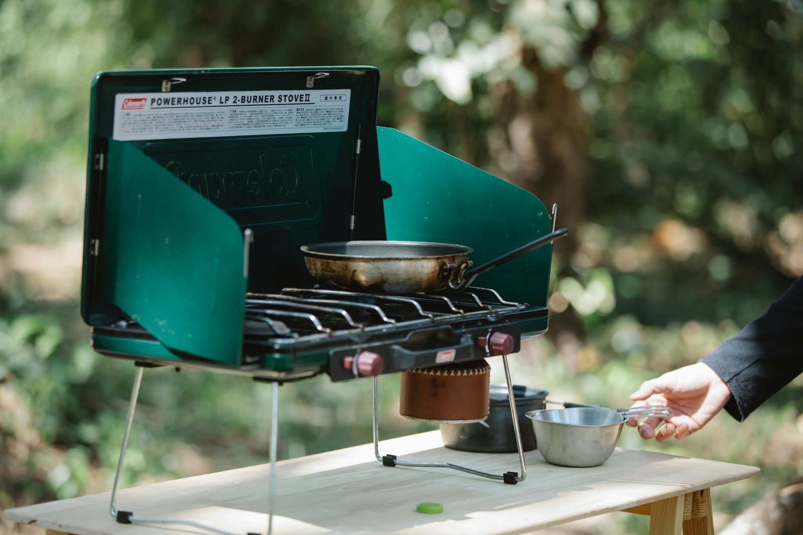 Crop unrecognizable male cooking on modern metal burner stove using skillet in forest – Food Planning